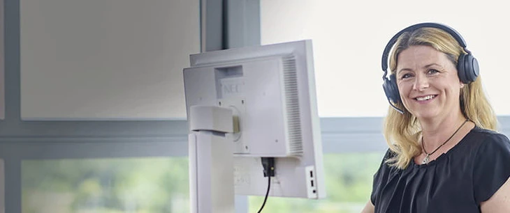 Freundliche Kundenberaterin mit technischem Equipment in hellem modernen Büro