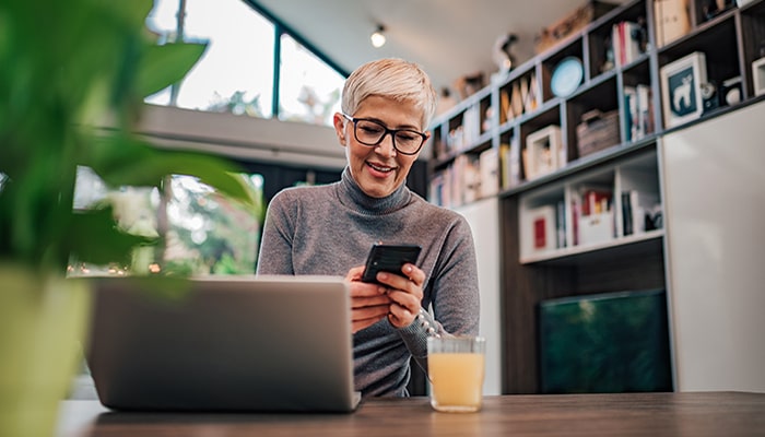Unternehmerin arbeitet mit Laptop und Smartphone an ihrem Schreibtisch.